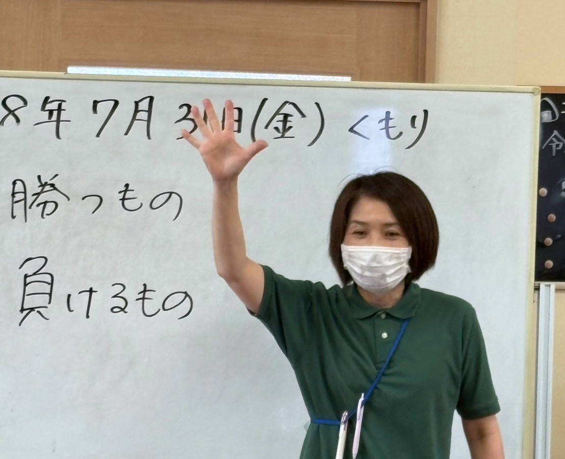 ホワイトボードの前で朝の会を進めるスタッフ